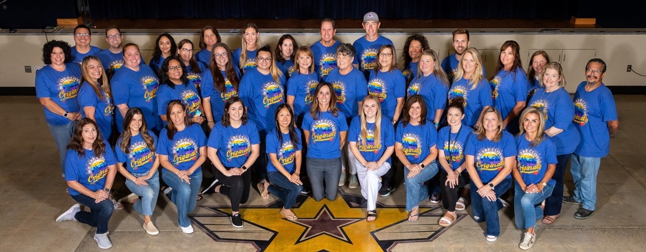 Gettysburg Staff wearing blue Clovis High shirts standing on MPR floor with school emblem